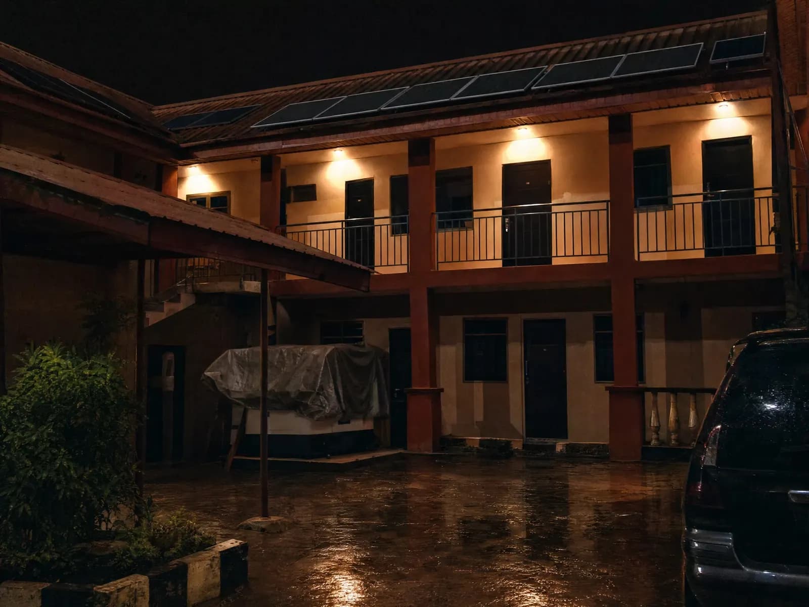 A lit guest house courtyard at night with the generator covered and idle