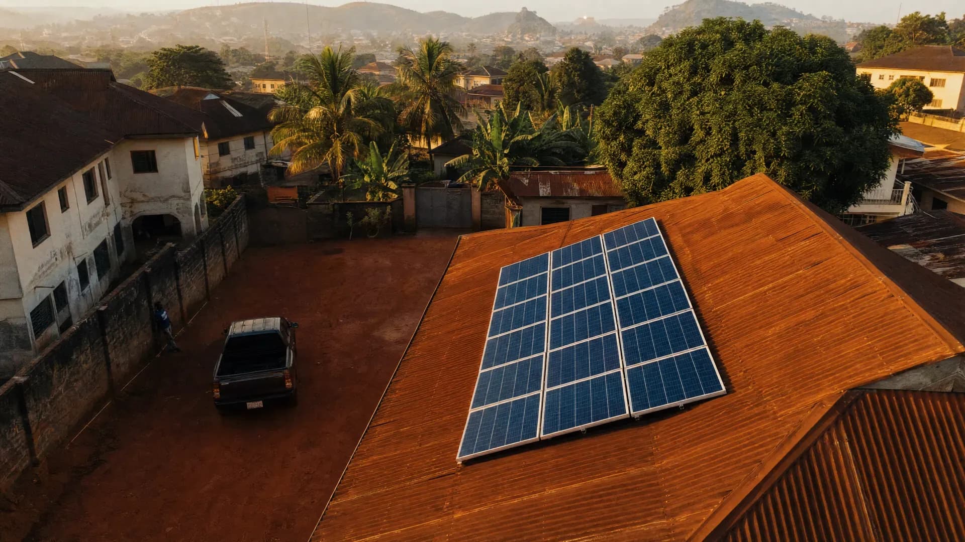 Aerial view of a rooftop solar array on a Nigerian residential compound at golden hour