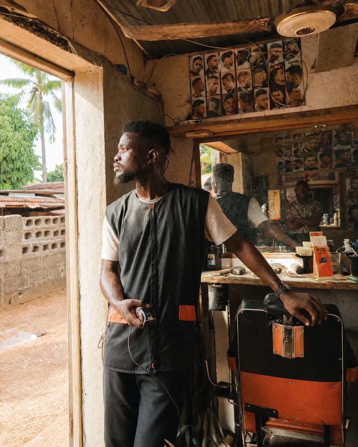 A barber standing in his shop holding clippers