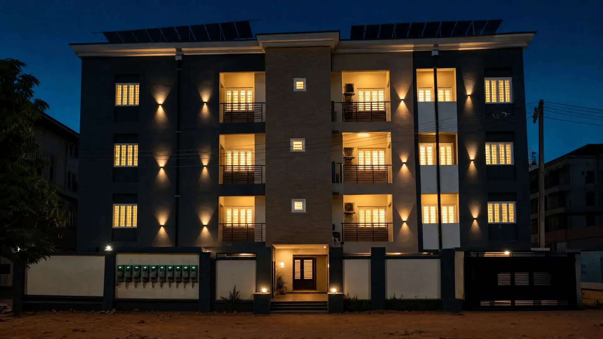 A Nigerian apartment block fully lit at dusk while neighbouring buildings sit dark